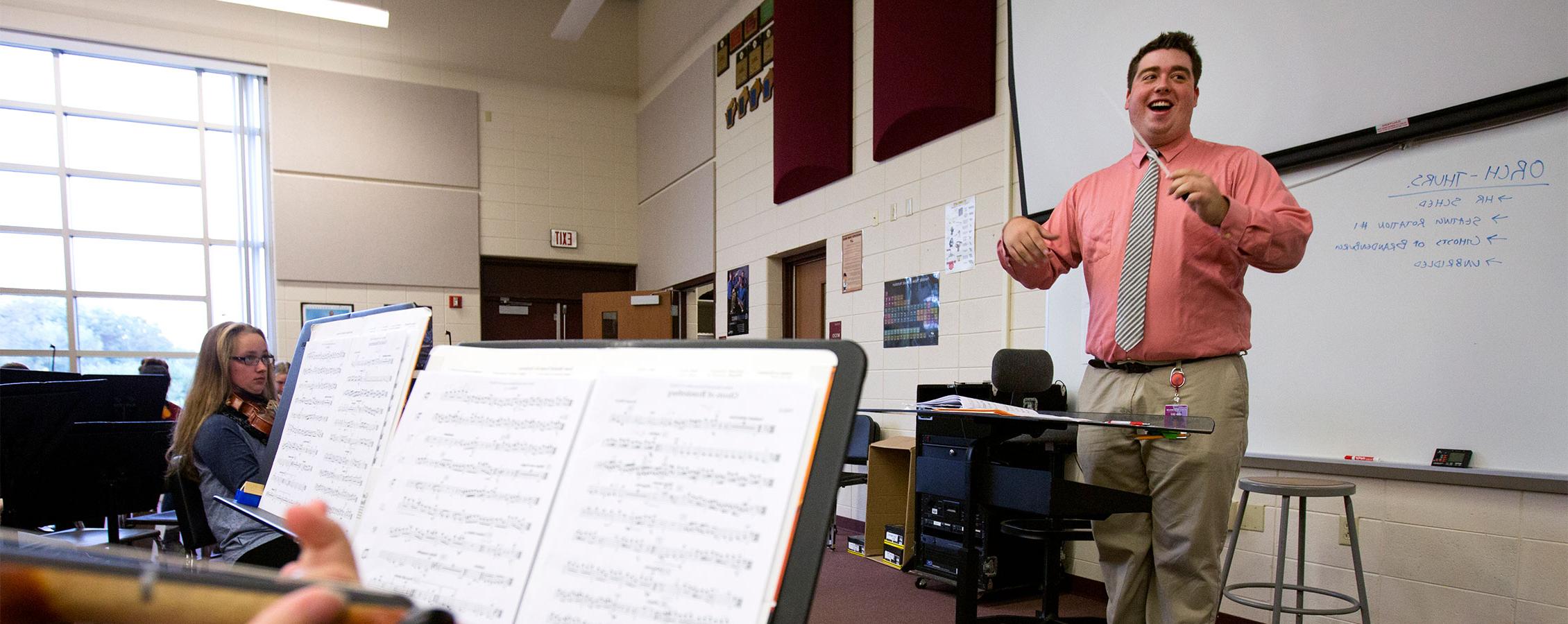 Middle school music teacher conducts band members.